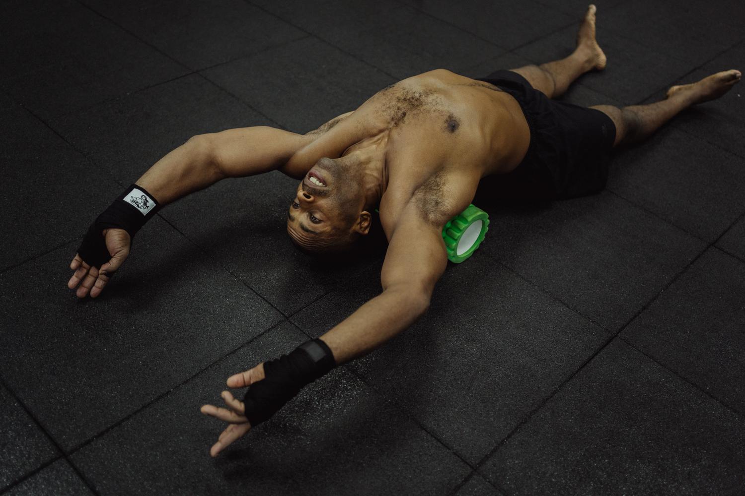 Hombre utilizando un rodillo de espuma (foam roller) para la recuperación muscular y prevención de rigidez.