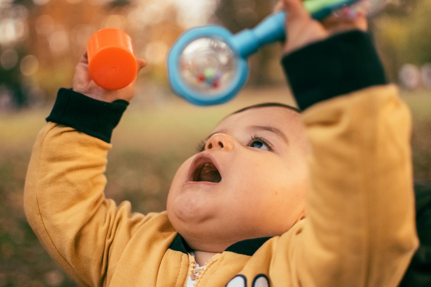 Bebé explorando un juguete colorido, ilustrando la fase de infancia y la estimulación sensorial temprana.