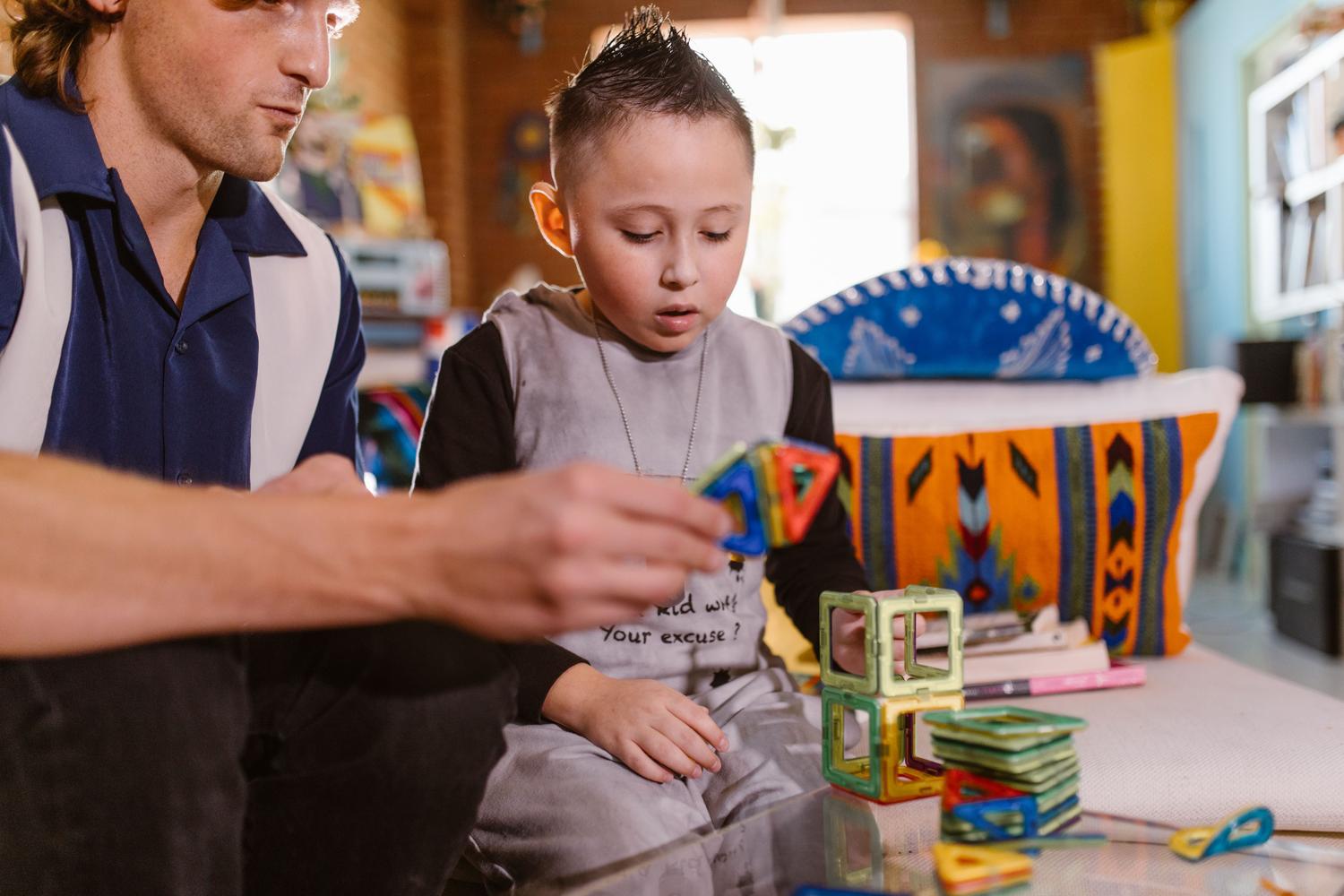 Padre e hijo jugando con bloques magnéticos, ejemplificando la interacción social y el desarrollo cognitivo.