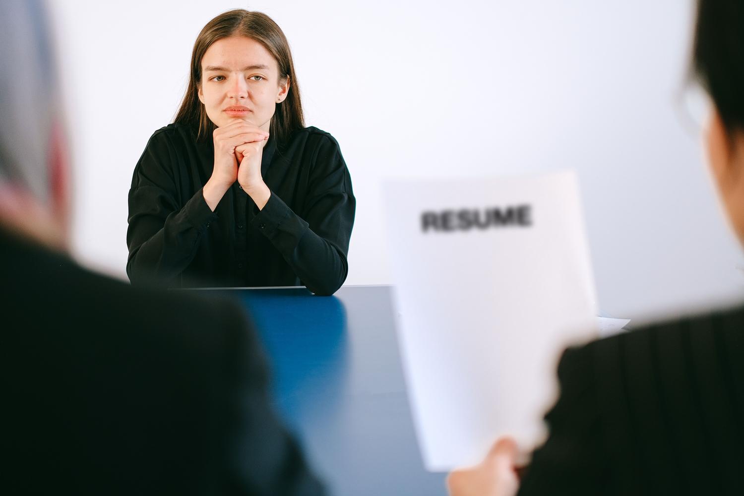 Mujer en una entrevista de trabajo frente a reclutadores con un currículum sobre la mesa