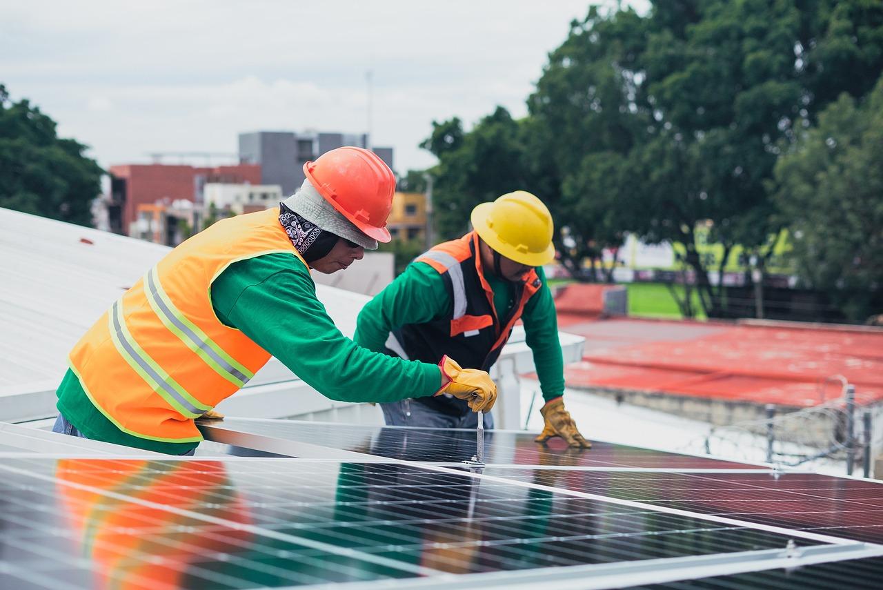 Técnicos instalando paneles solares en una azotea, ilustrando la implementación de acciones concretas de sostenibilidad en el sector empresarial.