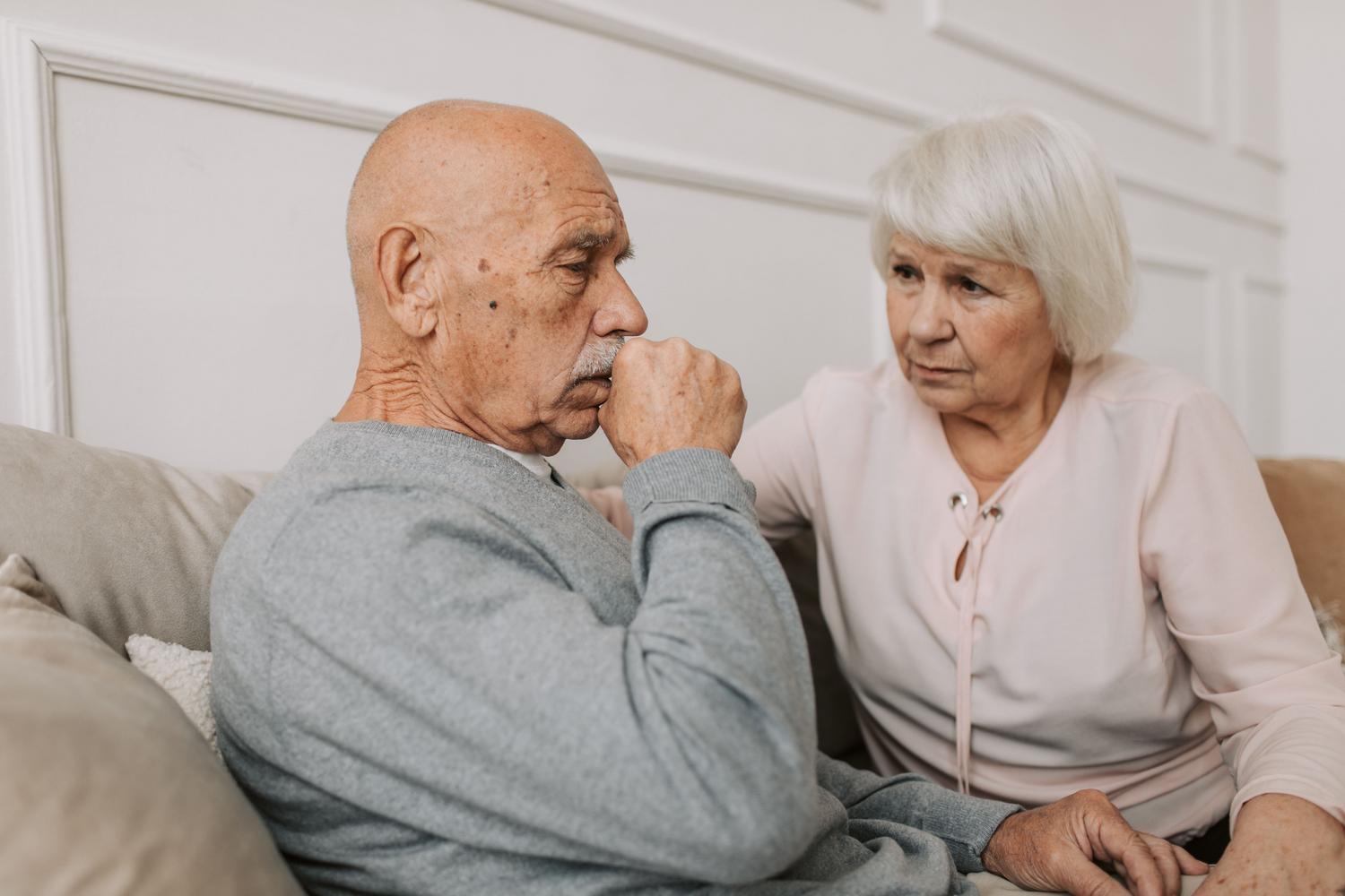 Pareja de ancianos en un sofá, donde la mujer muestra empatía y apoyo emocional hacia su esposo.