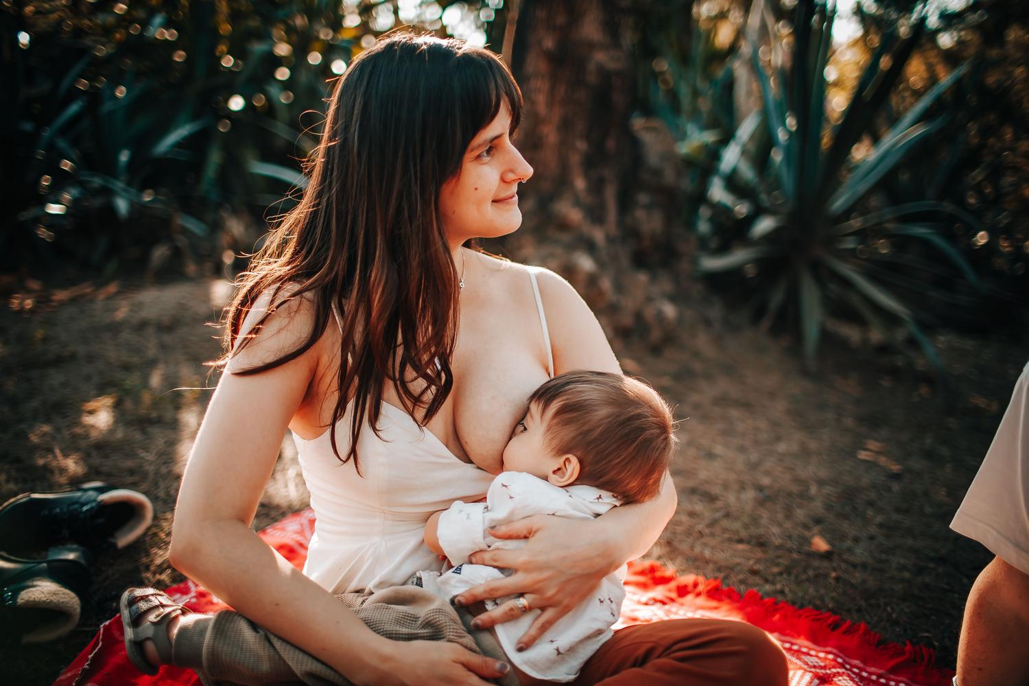 Madre amamantando a su bebé en un entorno natural al aire libre, representando la importancia de la lactancia materna exclusiva.