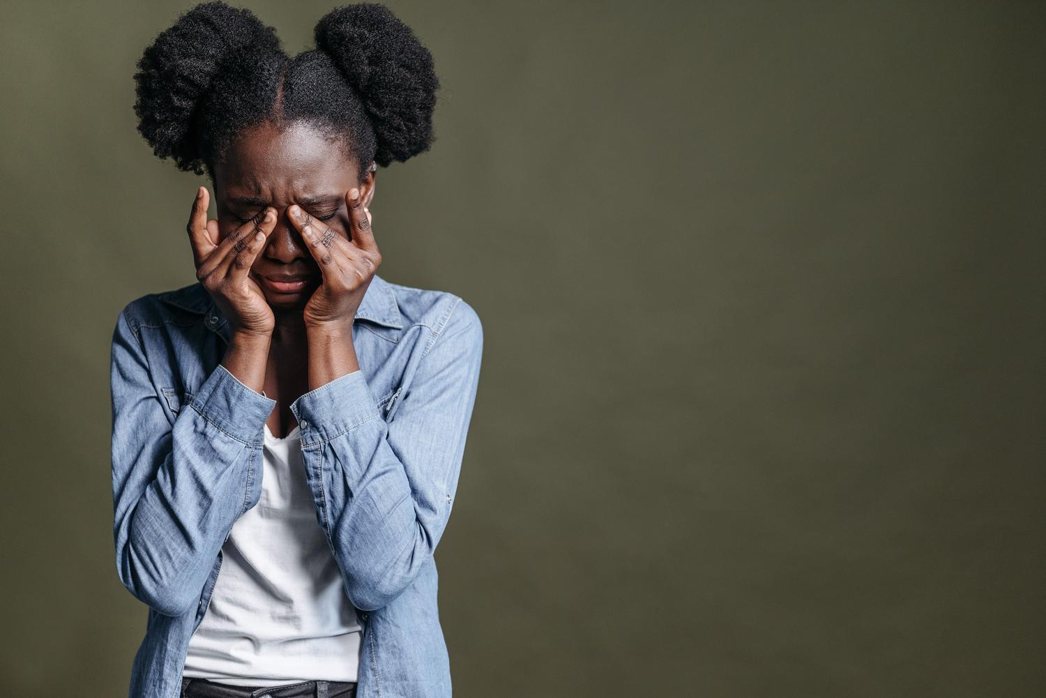 Mujer joven con expresión de agobio y estrés mental apoyando sus manos en las sienes