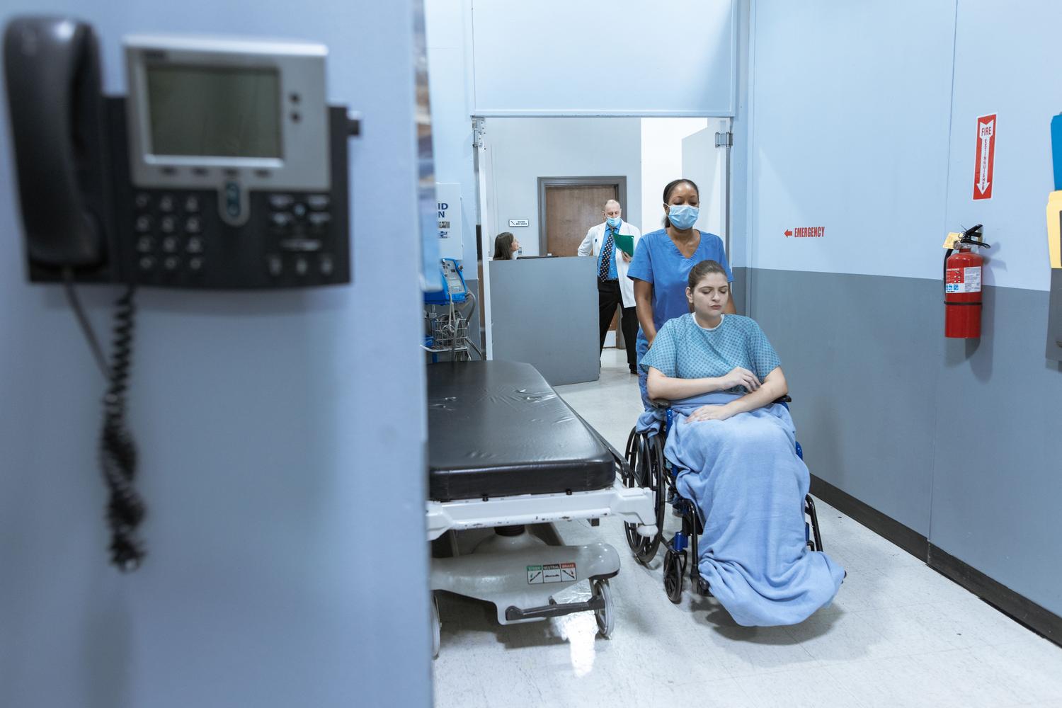 Enfermeira asistiendo a un paciente en silla de ruedas, ilustrando la fragilidad física asociada a la caquexia