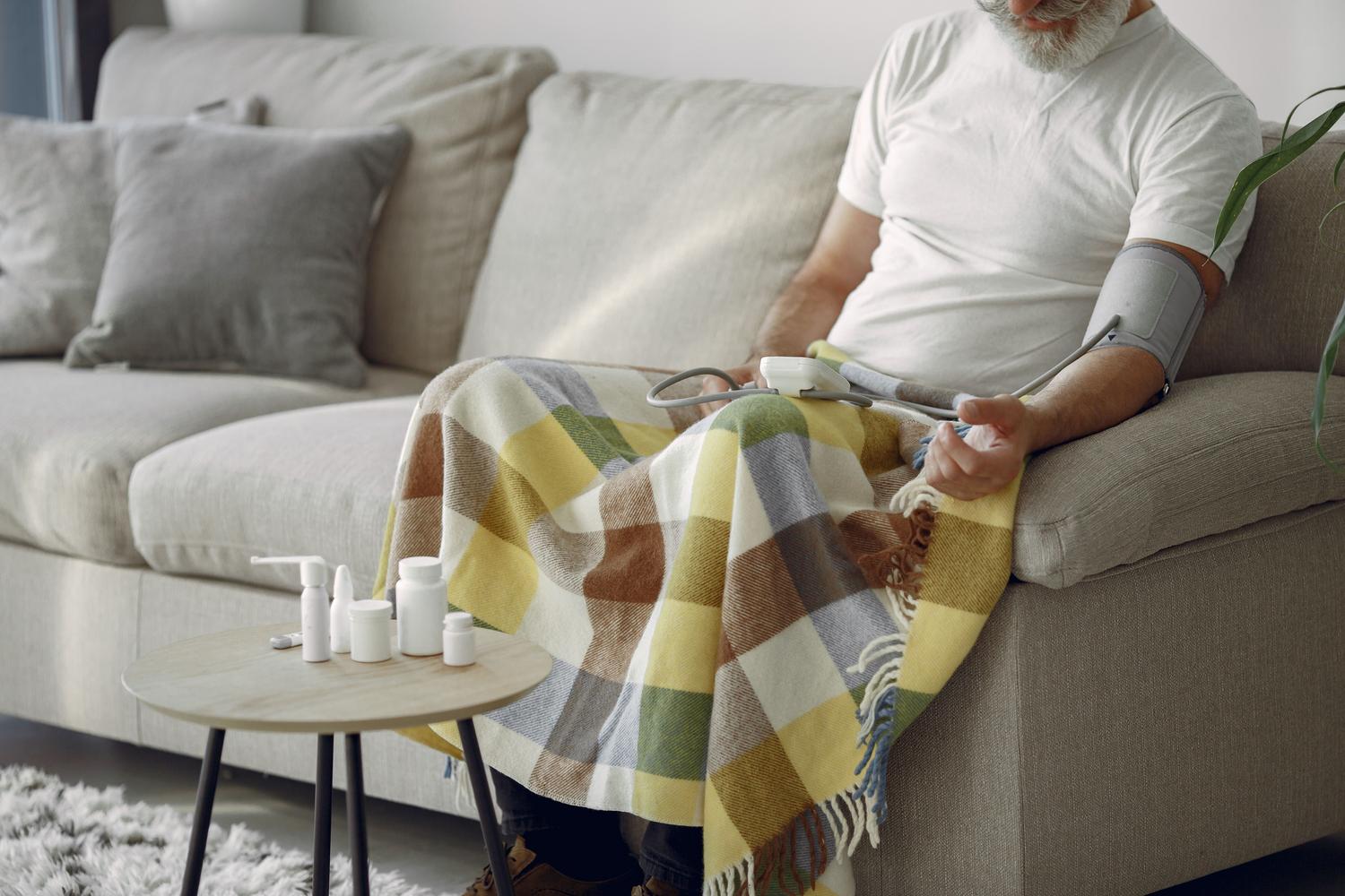 Hombre senior monitoreando su presión arterial en casa, simbolizando el cuidado preventivo de la salud masculina