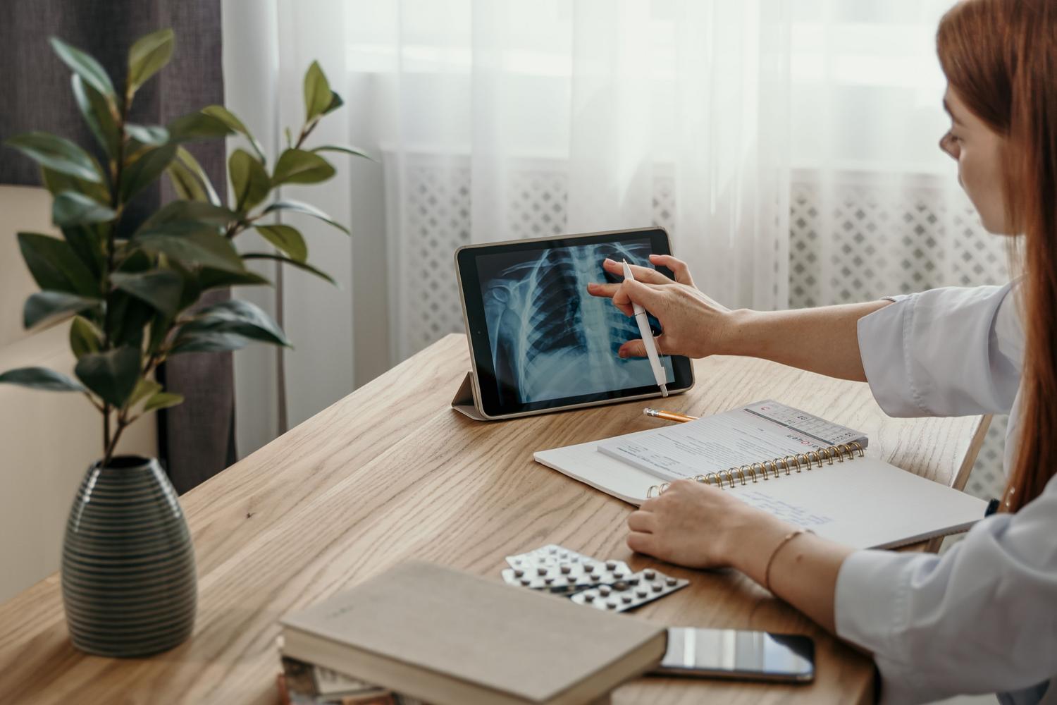 Profissional de la salud analizando una radiografía digital en una tablet, representando la estrategia de diagnóstico y simulación de exámenes.