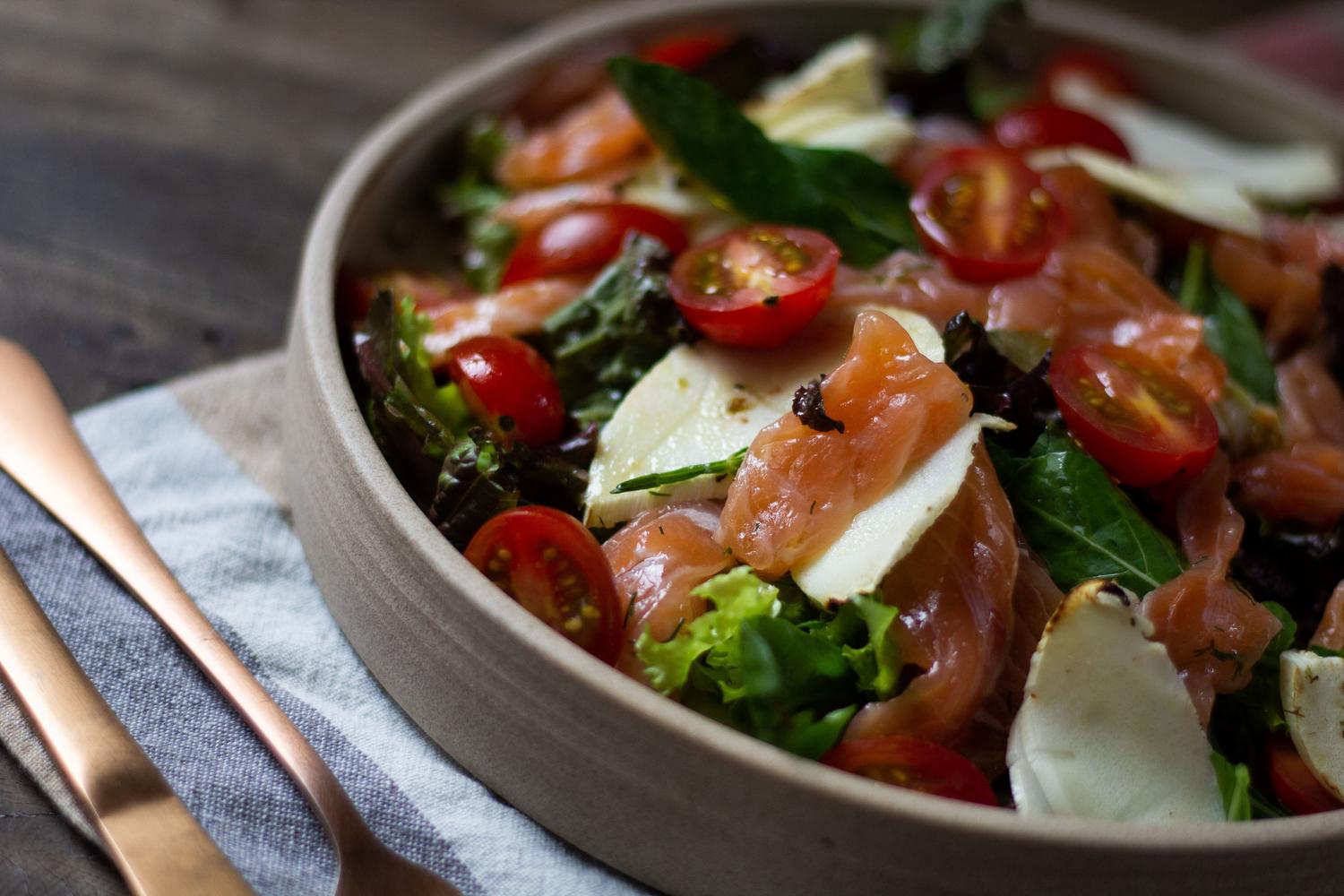 Ensalada vibrante de salmón ahumado, tomates cherry y hojas verdes, ideal para una cena ligera y saludable.