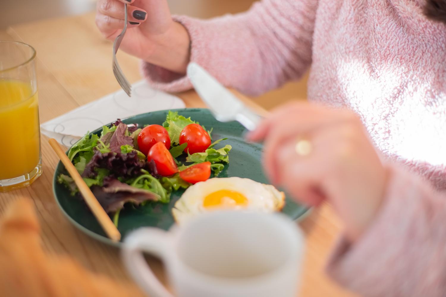 Plato de desayuno saludable con huevos, verduras verdes y zumo de naranja natural.