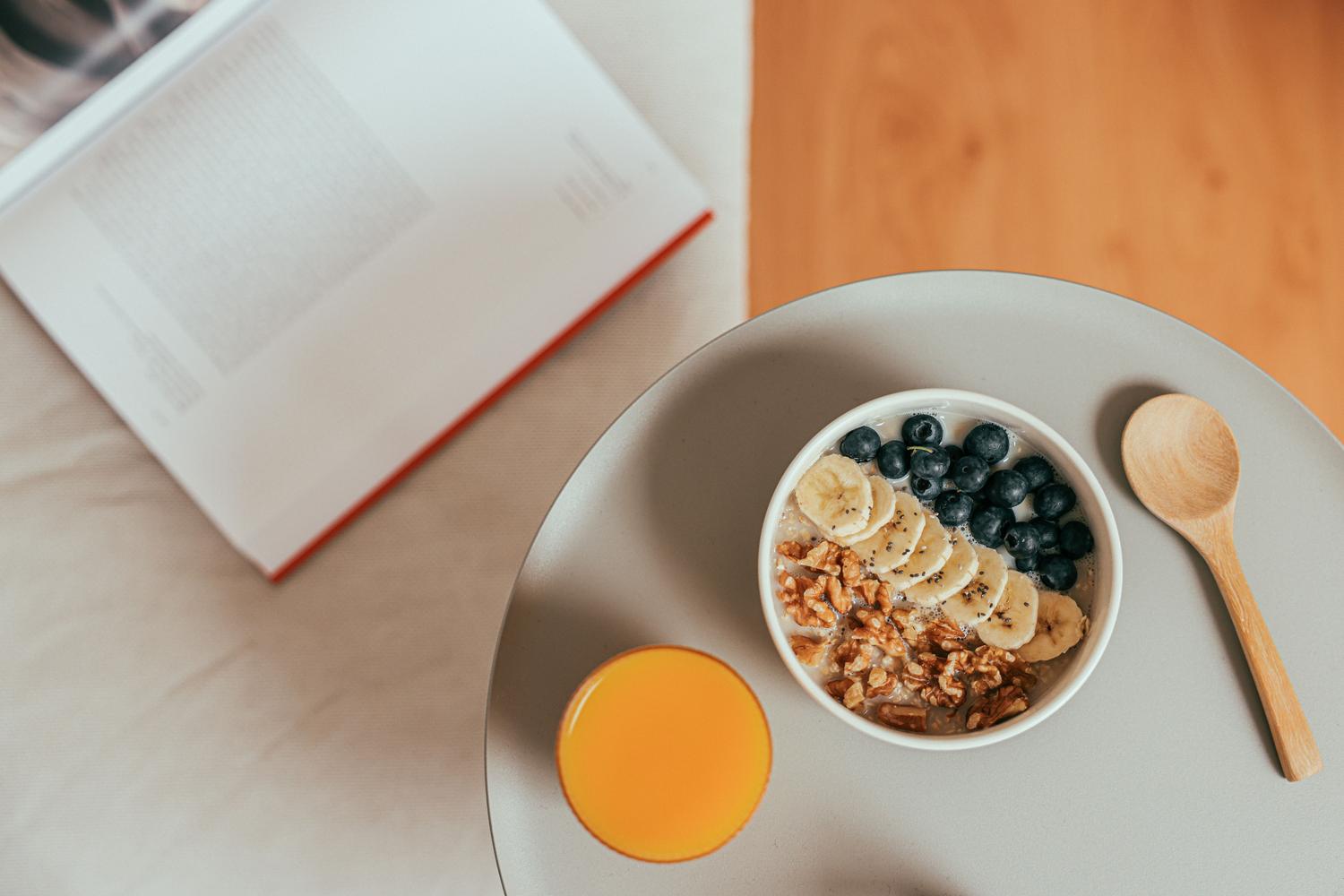 Bowl de avena con frutas frescas y un vaso de zumo de naranja, ideal para empezar el día con energía.
