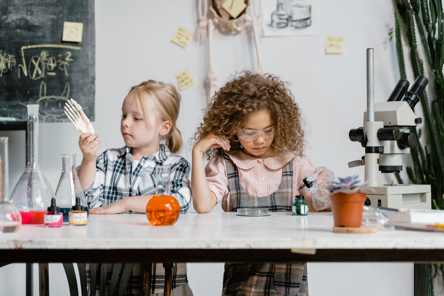 Dos niñas explorando la química y la biología en un entorno de laboratorio escolar.