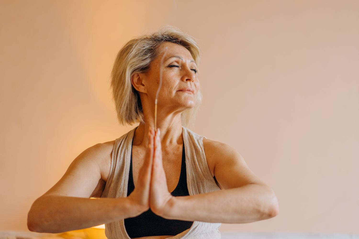 Mujer mayor meditando para gestionar el estrés y mantener el equilibrio mental durante la menopausia.