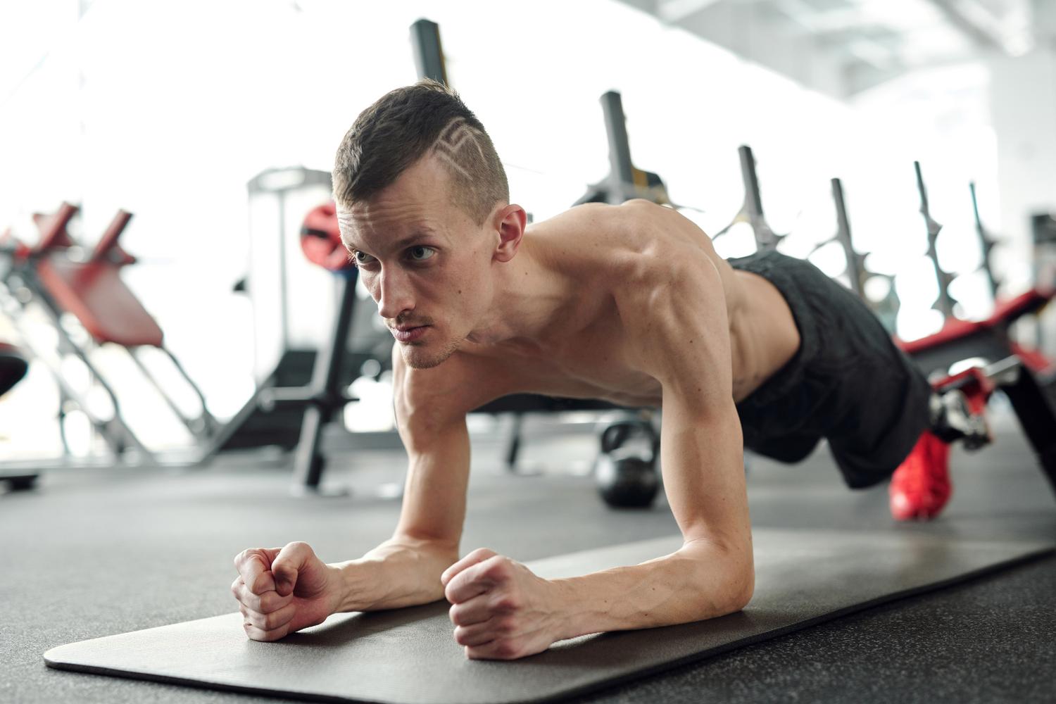 Hombre realizando una plancha frontal con técnica perfecta en un gimnasio
