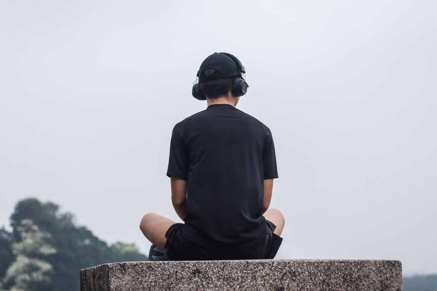 Joven meditando al aire libre con auriculares, representando la adaptación de las técnicas de atención plena al estilo de vida juvenil moderno.