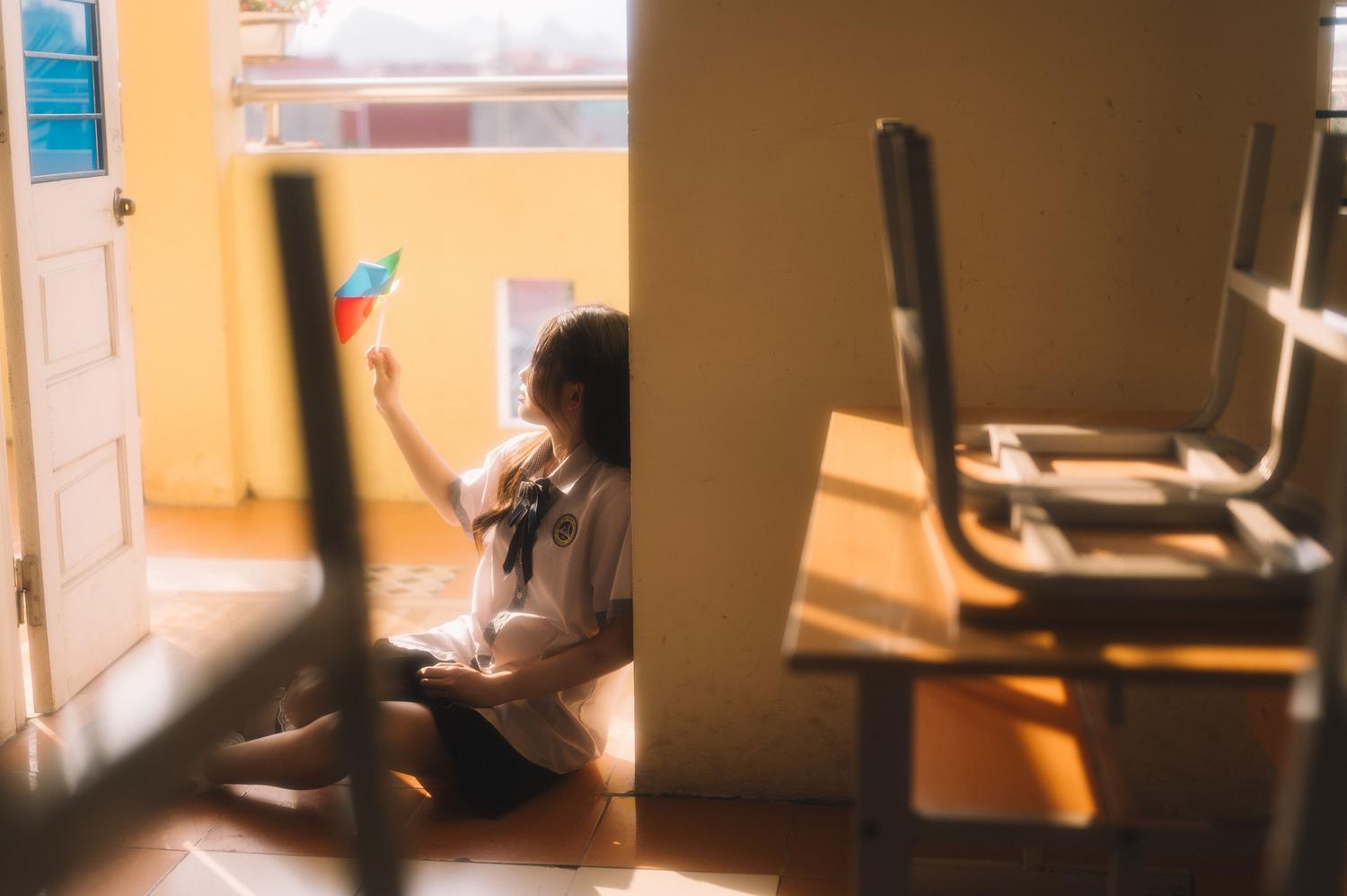 Estudiante relajándose en un aula iluminada por el sol, evocando un estado de paz y equilibrio emocional dentro del entorno escolar.