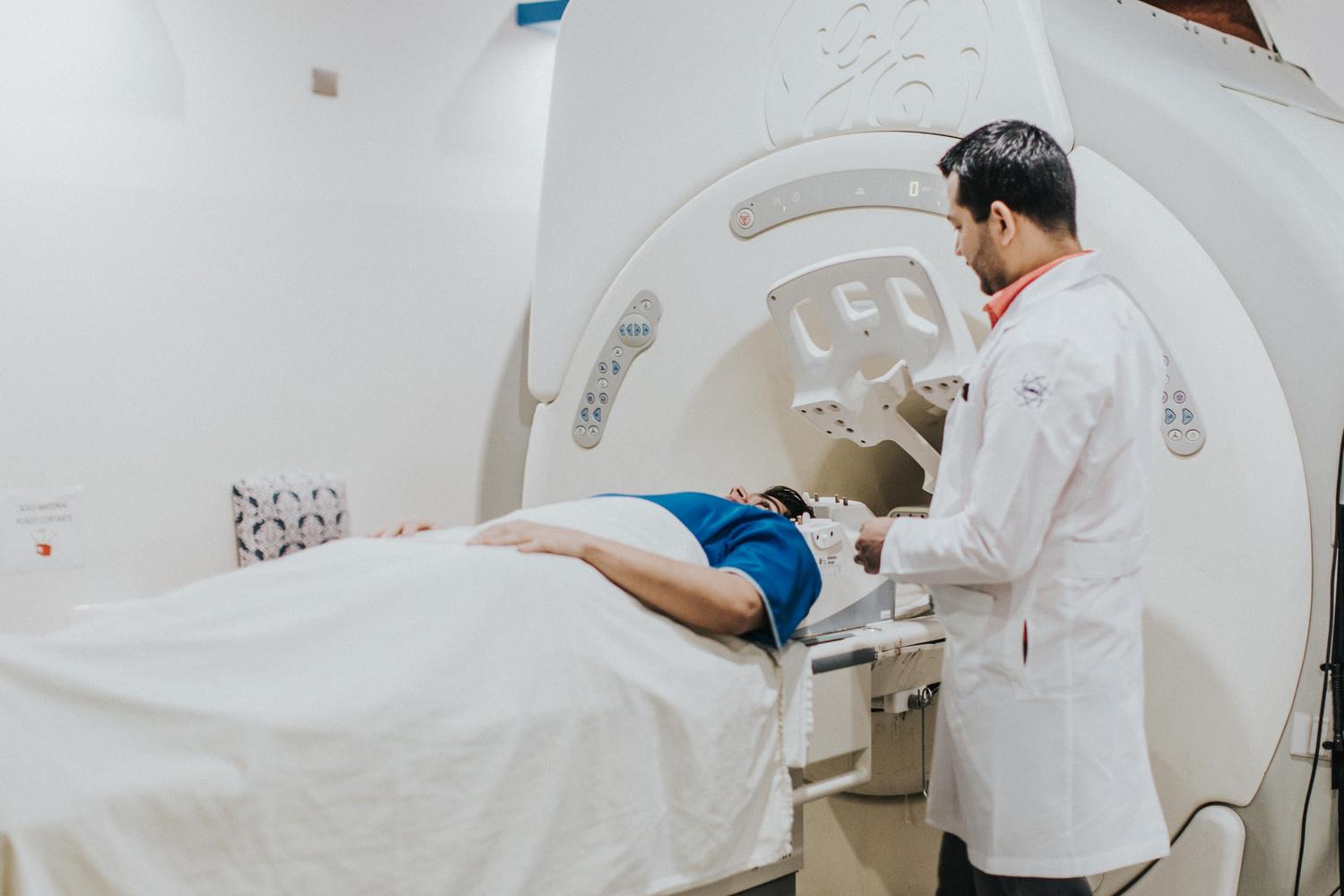 Paciente ingresando en una máquina de resonancia magnética asistido por un profesional de la salud en un entorno hospitalario.
