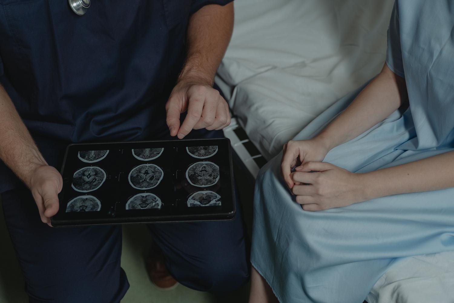 Médico especialista en neurología explicando los resultados de un escaneo cerebral a un paciente mediante una tableta digital.