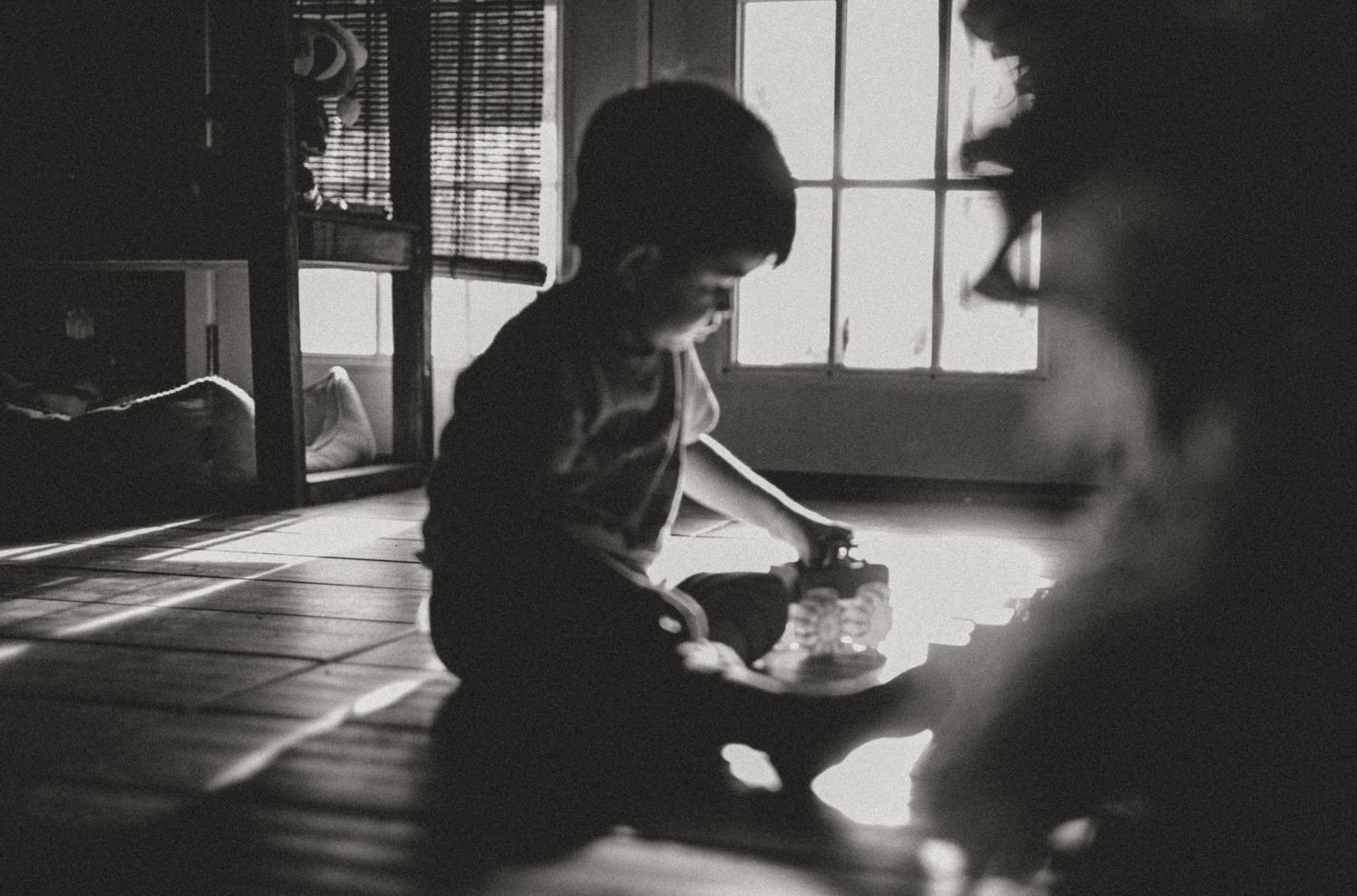 Escena íntima en blanco y negro de un niño jugando absorto, representando la conexión con el niño interior y la observación consciente.
