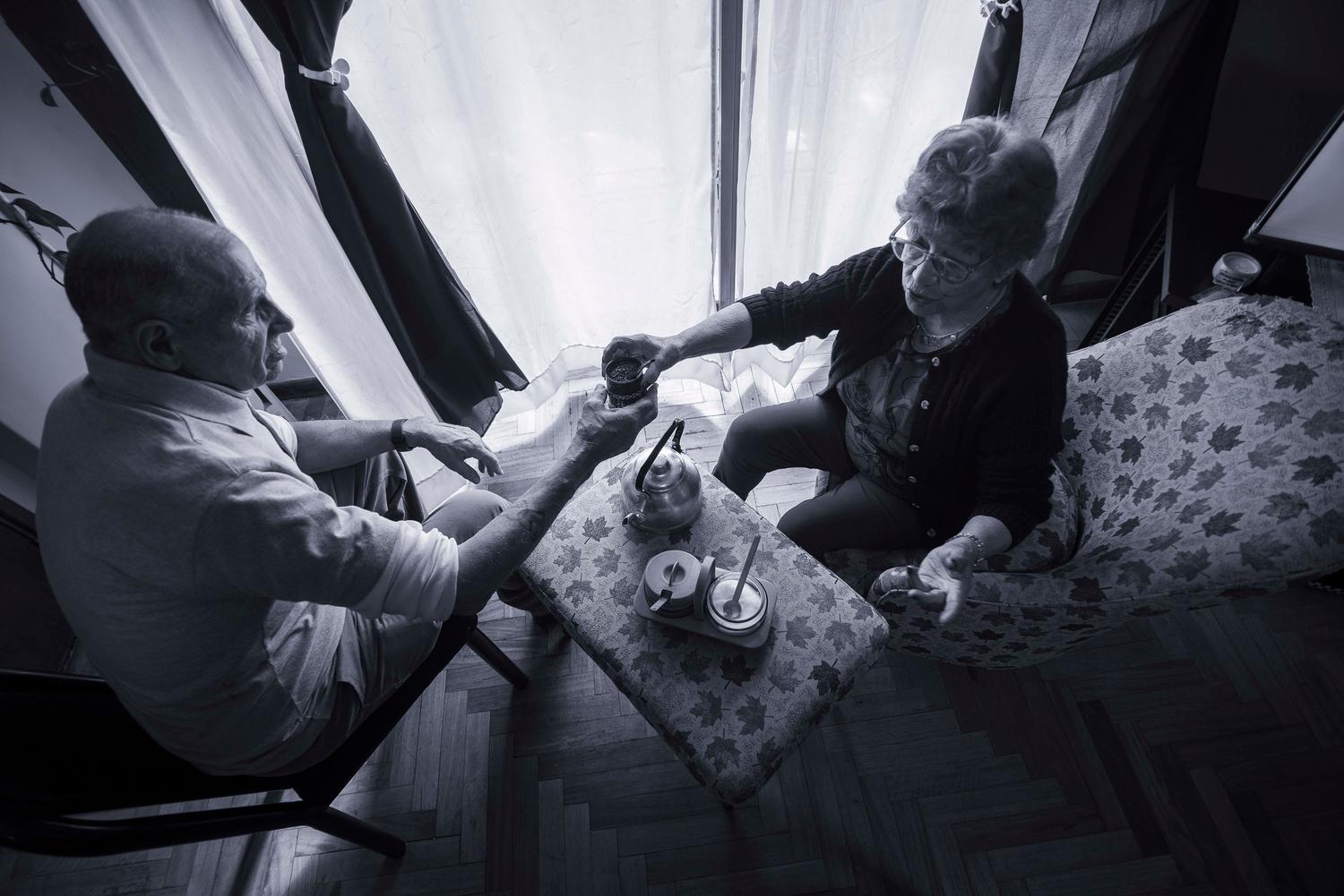 Imagen conmovedora en blanco y negro de una pareja de ancianos compartiendo un momento de calma en casa, ilustrando la conexión emocional y el apoyo.
