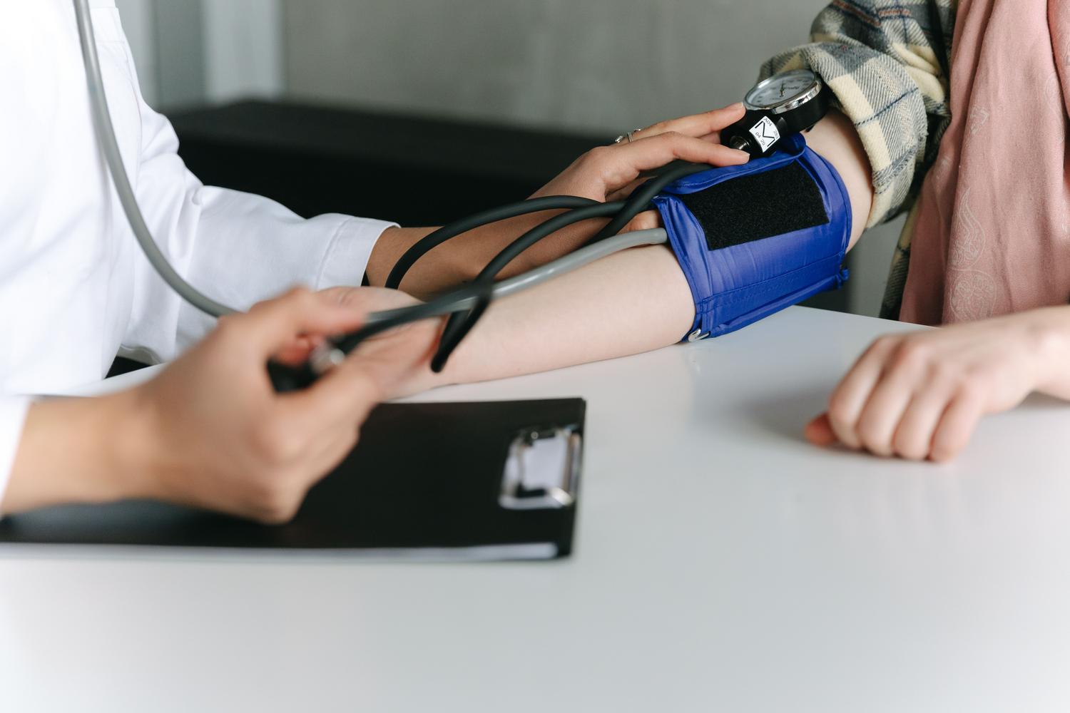 Profissional de la salud midiendo la pressão arterial de um paciente em um consultório médico.