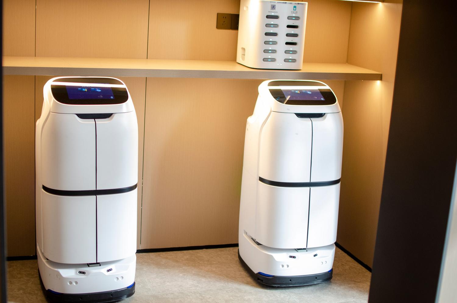 Robots de entrega autónomos en un entorno moderno, ilustrando la automatización logística y la redução de carga laboral humana.