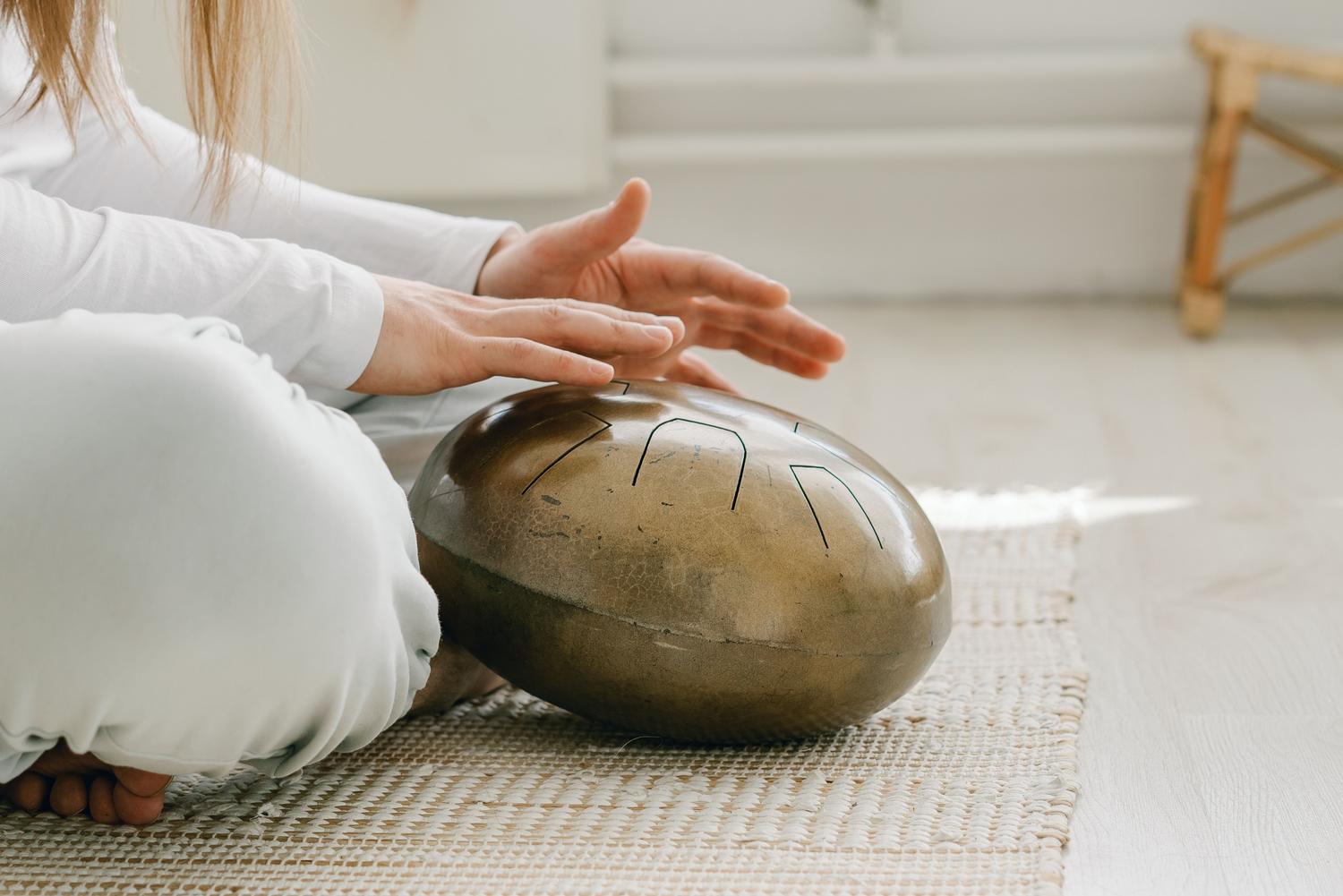 Una persona tocando un tambor de lengua (tongue drum) en un ambiente relajante, simbolizando la musicoterapia para el manejo del dolor y el estrés.