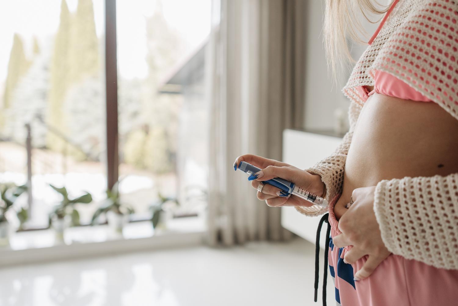 Mujer administrándose una inyección de insulina con un dispositivo tipo pluma en el abdomen