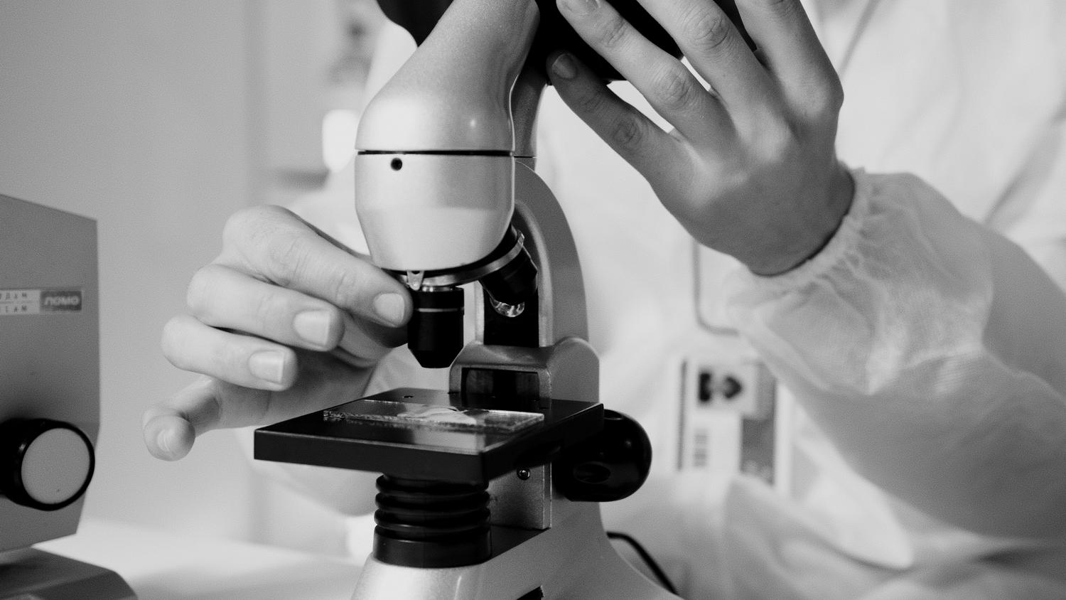 Profesional de salud analizando una muestra bajo el microscopio en un laboratorio clínico para evaluar la motilidad espermática.