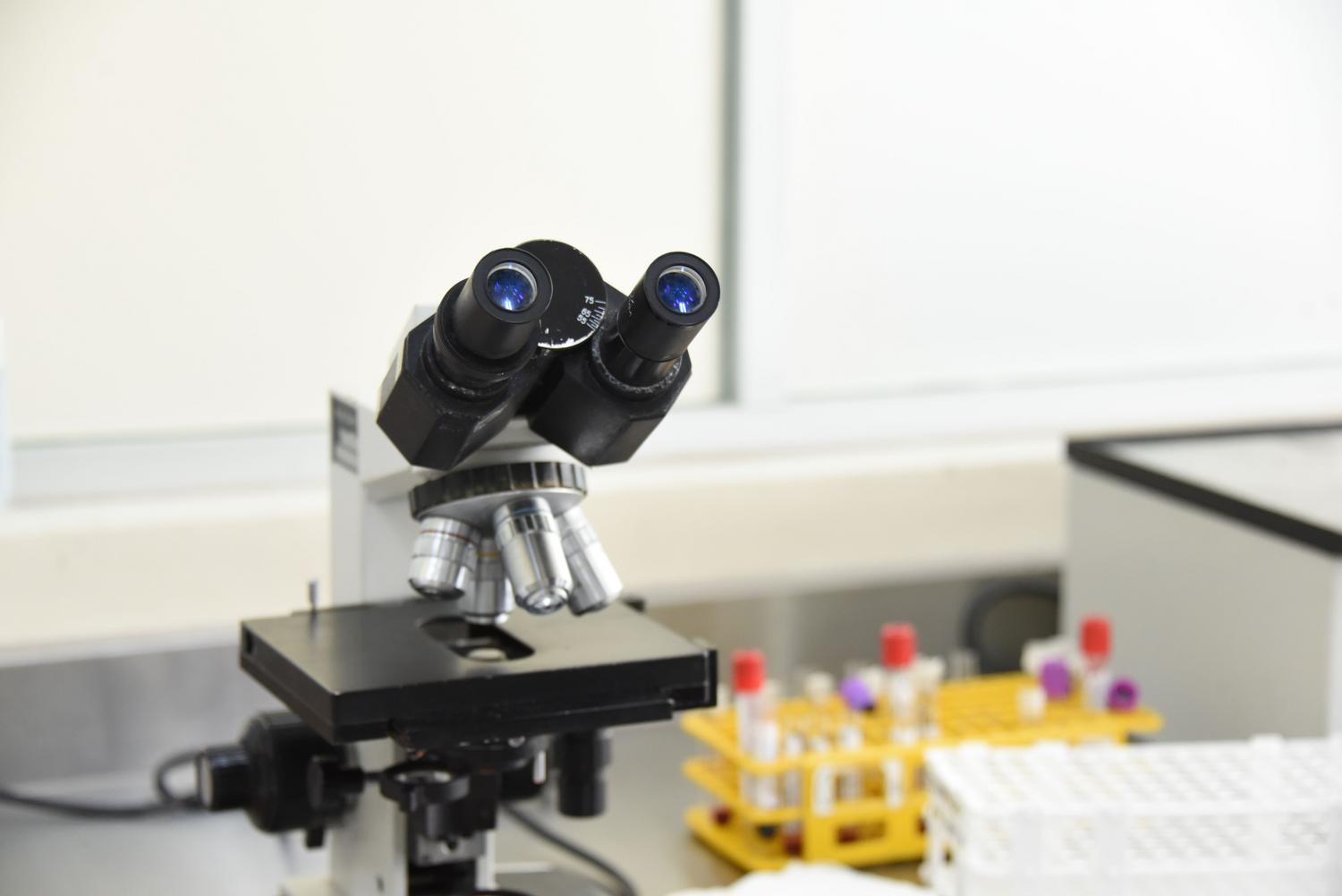 Microscopio de laboratorio y tubos de ensayo para el estudio de la naturaleza histológica y celular de los biomarcadores.