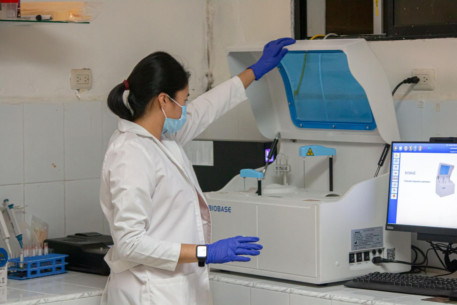 Científica operando un equipo de análisis bioquímico automatizado en un entorno de investigación médica.