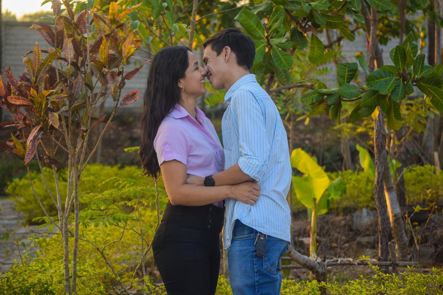 Pareja joven compartiendo un momento íntimo y romántico en un parque soleado, reflejando la pasión y la conexión emocional.