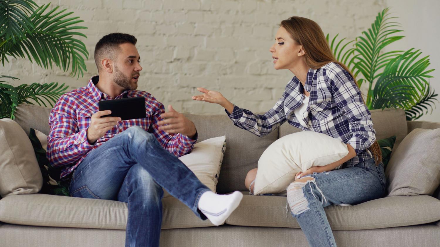 Pareja teniendo una discusión en el sofá de su casa, representando los conflictos y las señales de alerta en una relación.