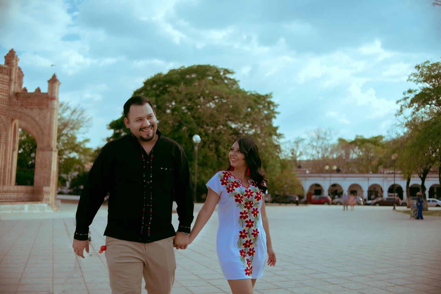 Pareja feliz caminando de la mano por una plaza pública, simbolizando la estabilidad y la amistad como base de la relación.