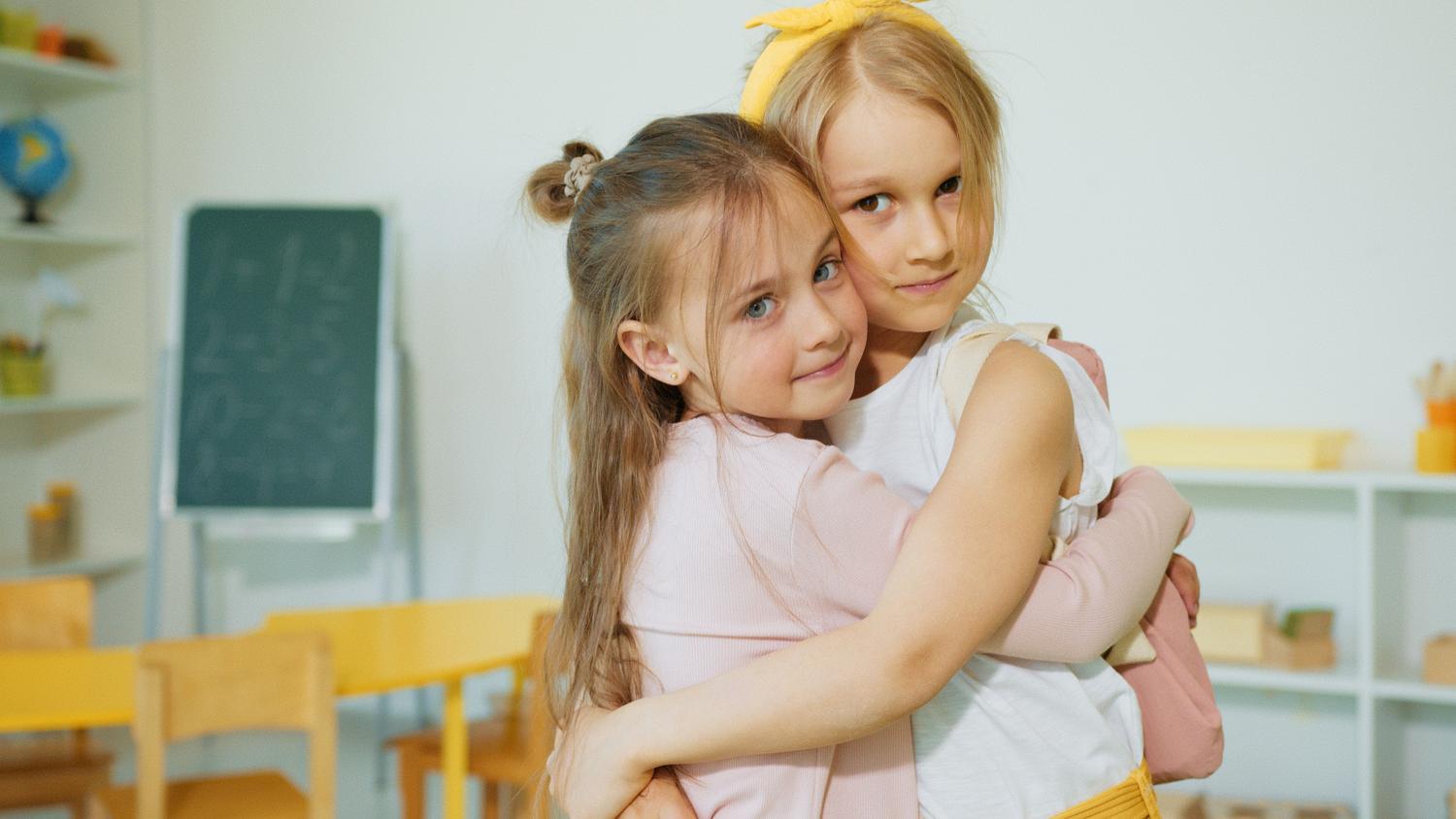 Dos estudiantes abrazándose en un aula, representando los factores protectores, la empatía y el apoyo emocional entre pares.