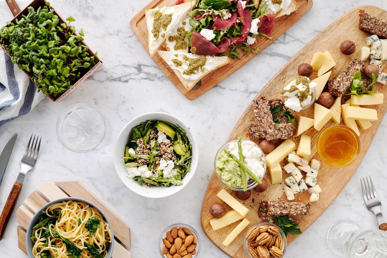Tabla de quesos, frutos secos y pasta, ilustrando alimentos con alta densidad energética