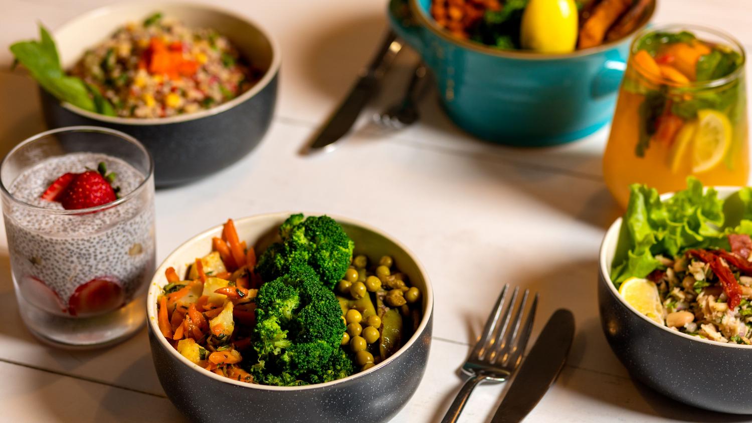 Variedad de platos saludables con brócoli, zanahorias y pudin de chía para ilustrar alimentos de baja densidad calórica