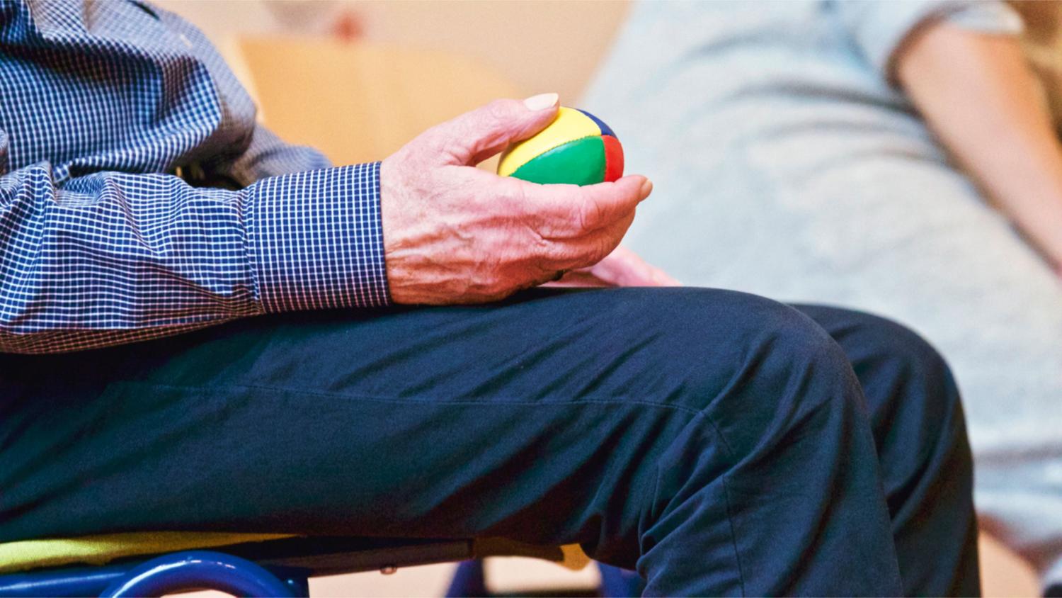 Persona mayor realizando ejercicios de fisioterapia con una pelota terapéutica para mantener la movilidad de las articulaciones